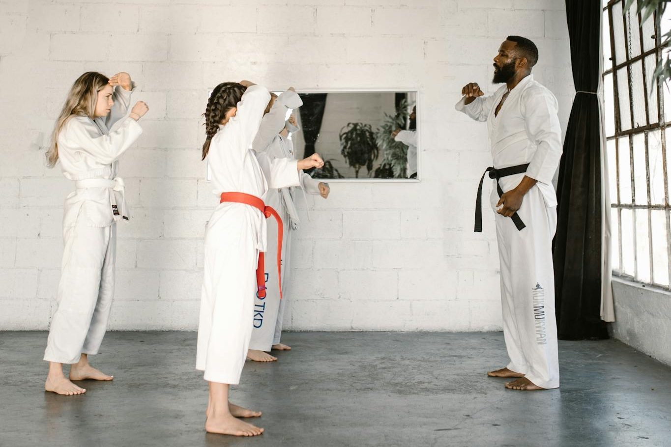 Martial arts instructor teaching young students karate techniques in a bright studio.