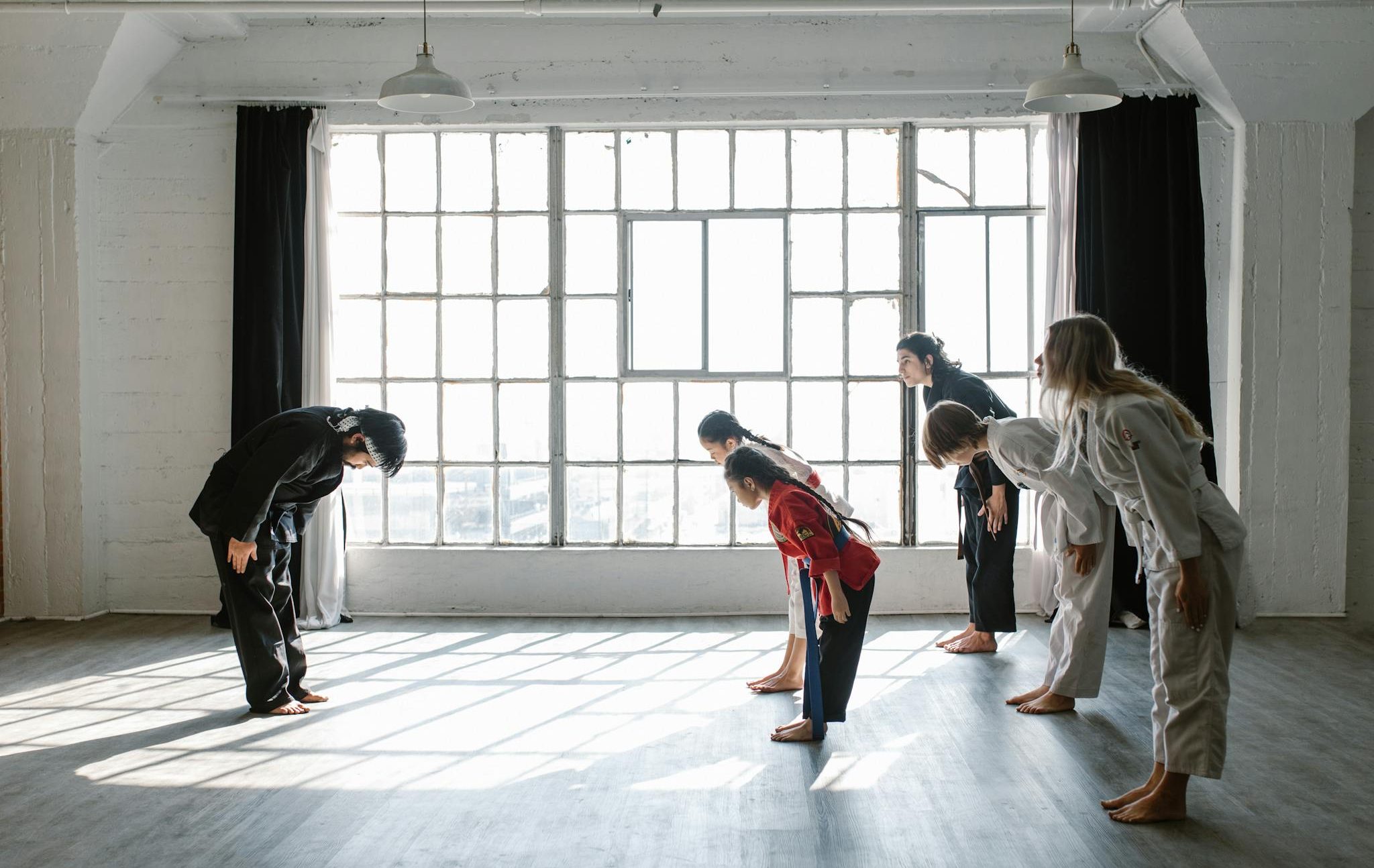 Martial arts students bowing in a sunlit dojo. Perfect for fitness and sports themes.